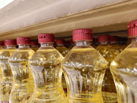 Bottled vegetable oils are arranged on supermarket shelves.