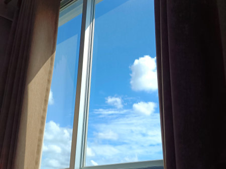 The window from the bedroom overlooks the daytime sky.の写真素材