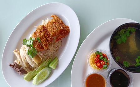 Boiled Chicken Rice Mixed with Fried Chicken Served with broth and dipping sauce, top view. The most...