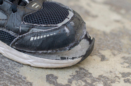 closeup view broken old black sneakers on the floorの写真素材
