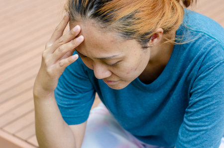 Asian women sitting touch their temples right side, feel a headache or dizzy, feeling tired. need painkillersの写真素材