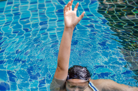 Asian woman asking for help is drowning due to leg cramp in swimming poolの写真素材