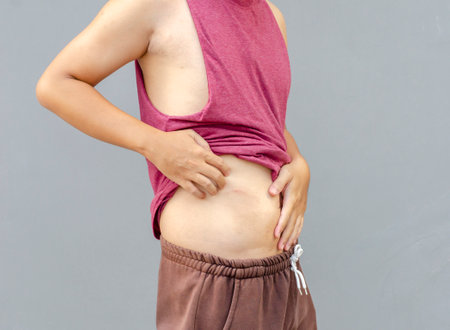 Asian man scratching itch with hand on abdomen area, health care conceptの写真素材
