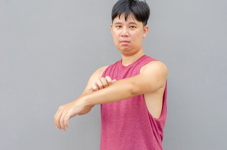 Asian man scratching itch with hand on left arm area, health care conceptの写真素材