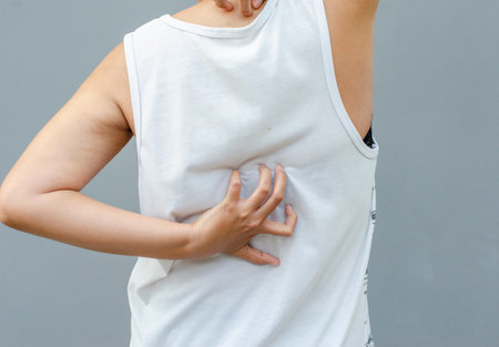 young asian woman scratching itch with hand on dorsal area, health care concept, dermatosisの写真素材