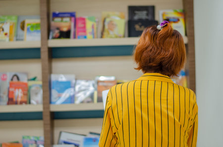 young woman standing and reading in the library to learn