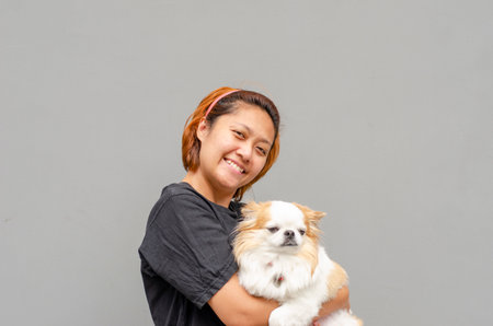Young Asian woman standing holding a chihuahua dogの写真素材