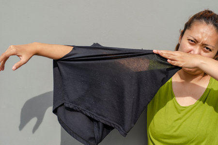 young Asian woman shows her arm to the hole of her old black pants, torn buttocks after being used for a long time. grey backgroundの写真素材