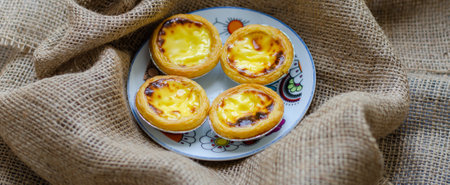 Small egg tarts on a round plate, dessert. on brown fabric background. Wallpaperの写真素材