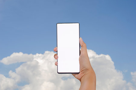Asian women hand holding smartphone, blank screen. Sky background. for text inputの写真素材