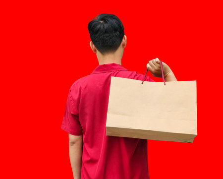 Asian man stands, her back to the viewer, clutching shopping bags. on red background. Chinese New...