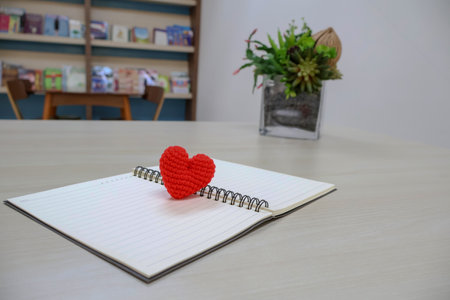 Side view. heart made of yarn on a notebook with lines page for writing with artificial flowers as decoration. Valentine Day Themeの写真素材