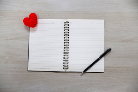 Notebook with lines and hearts and black pen on wooden table background. Valentine Day Themeの写真素材