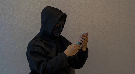 Scammers, masked individuals holding phones, criminal networks stealing information through telephoneの写真素材