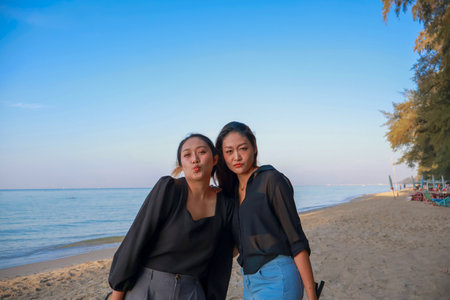 happy asian women family of two sibling on the sea and beach on blue sky background. Travel Rayong Province, Thailand.の写真素材