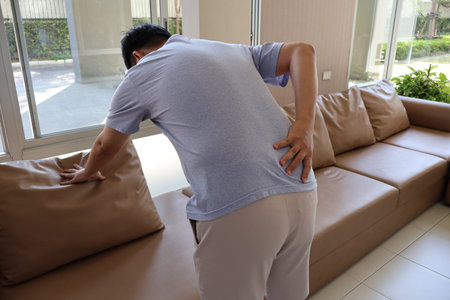 Asian man holding his lower back from back pain or muscle inflammation. Backache in office syndrome.の写真素材
