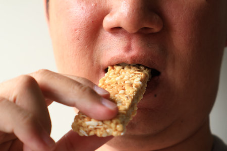 Close up view of Young Asian man eating healthy granola bar honey  flavor. wellness conceptの写真素材