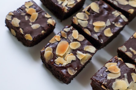 Chocolate Brownies cake pieces with topping almond slice on white background. Closeup and side viewの写真素材