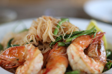 Side view of Stir-fried Vermicelli with Water Mimosa with shrimps in plate on wooden background....