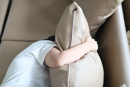 Asian woman hugging a pillow on the sofa feeling sad and depressed.