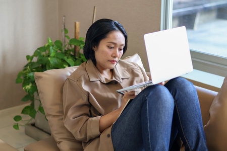 Asian businesswoman sitting on sofa working with laptop, Work from homeの写真素材