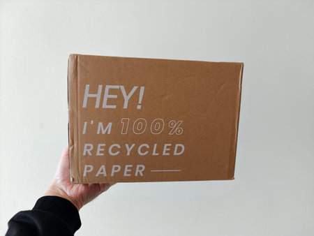 The hand picks up a cardboard box made from recycled paper. An eco-friendly concept.の写真素材