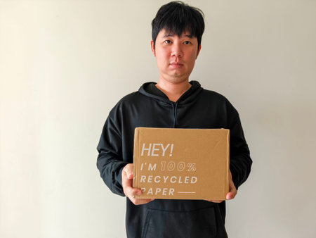 The young man is holding these cardboard boxes made from recycled paper, an environmentally friendly concept.の写真素材