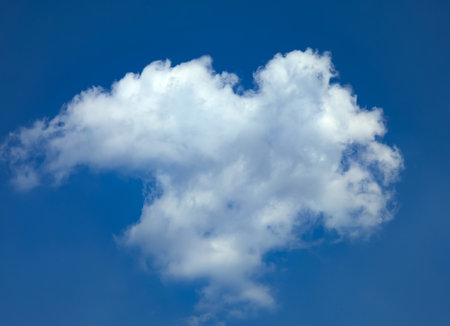 A light cloud hovering above the ground on a blue background. Looking up at the sky. Gradual sailing with the wind.の写真素材
