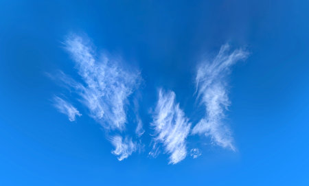 Beautiful blue sky background with cirrus clouds. Large and small vapor structures are arranged in a...
