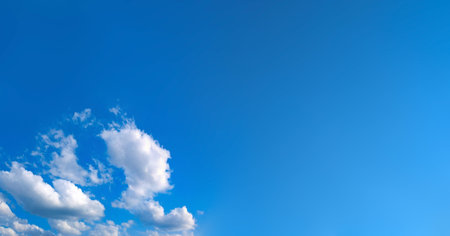 A feathery fanning of cumulus clouds in a serene, empty blue sky atmosphere. Panorama of cirrus and cumulus clouds viewed from below. Dramatic meteorological celestial spectacle. Blue skies in turmoilの写真素材