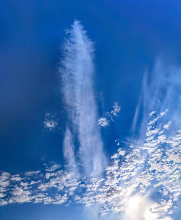 A relaxed cloud, decomposing in the wind, spreads into a pancake shape. The lazy, hot structure of the steam. Bright blue sky with some cirrus clouds. Cirrus plume vertical splash fog.の写真素材