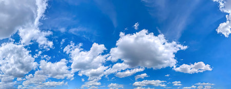 A landscape of light, big and small clouds, scattered across a blue sky. A panoramic view of the bright expanse. A wide banner for a website. Wide panorama of multi-level cumulus fly cloud.の写真素材