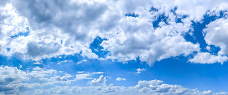 White high-altitude clouds almost completely obscure the blue sky. Light vapor appears against the blue background. An arch of cirrus clouds curves cloudscape panoramic across the wide field of view of the atmospheric spectacle.の写真素材