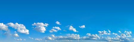 Cloudscape white clouds panorama. A wide panoramic of low-flying cumulus cloud of varying sizes. Voluminous space-occupying clouds of steam against a blue background. The sky in serene motion.の写真素材