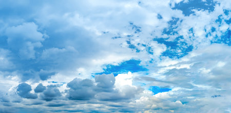 White high-altitude clouds almost completely obscure the blue sky. Light vapor appears against the blue background. An arch of cirrus clouds curves cloudscape panoramic across the wide field of view of the atmospheric spectacle.の写真素材