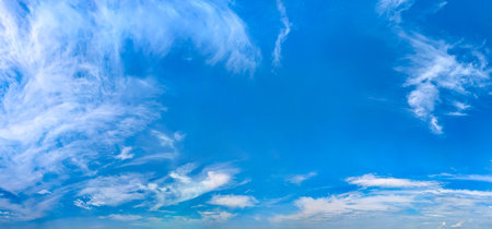 Sky is blue and clear with clouds. The sun is shining brightly. Wide panorama of heaven with cumulus cirrus cloud. Serene quiet warm scene.の写真素材