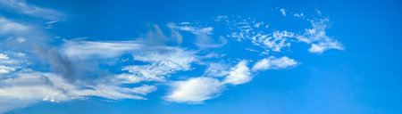 Beautiful blue sky background with cirrus clouds. Large and small vapor structures are arranged in a chain, flowing smoothly along the horizon line. Wide website banner.の写真素材