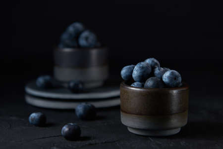 Fresh organic blueberries in a bowl on black backgroundの写真素材