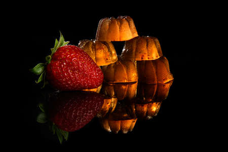 Transparent strawberry marmalade with fresh strawberries on a black background with reflection.の写真素材