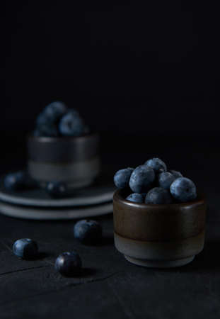 Fresh blueberries in a gray ceramic bowl on black concrete and black background.の写真素材