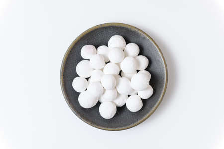 White sugar balls in a gray ceramic plate on a white background. close up view.の写真素材