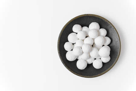 Sweet white sugar balls on a gray ceramic plate isolated on a white background. Close up, top view, copy space.の写真素材