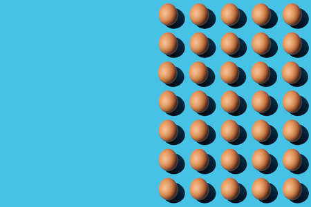 A pattern of brown chicken eggs on the right half of the blue background. Left side for copy space, close up, top view. Horizontal.の写真素材