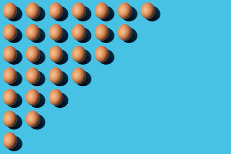 A pattern of brown chicken eggs lying diagonally on the upper left half of the blue background. Right side for copy space, close up, top view.の写真素材