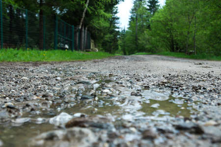 Road full of ballast and trees in the distance - road with water