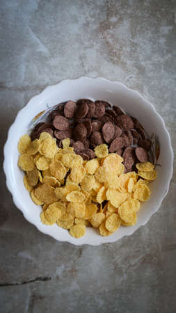 Bowl of black and yellow cereals on grey background top viewの写真素材