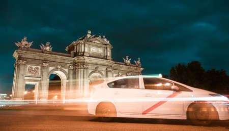 Puerta de Alcala (Alcala Gate) at night in Madrid, Spain with a car in motionの写真素材