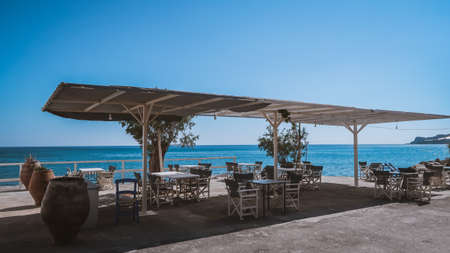 Cozy tables and chairs in an open restaurant near the sea in Keratokampos, Creteの写真素材