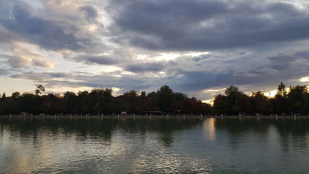 Trees and clouds reflecting in the water during sunset in Buen Retiro Park Madridの写真素材