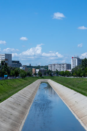 Iasi, Romania, 7th June 2021: The water canal going through the city with high buildings and greenery against a cloudy skyのeditorial素材